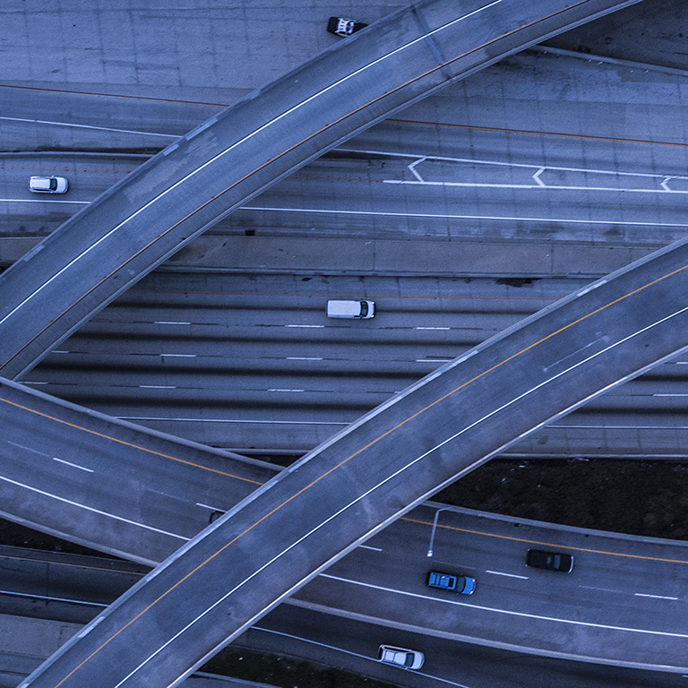 Vehicles move along multiple highways in an urban area during the night. The roads twist and turn in different directions, creating complex pathways for traffic.