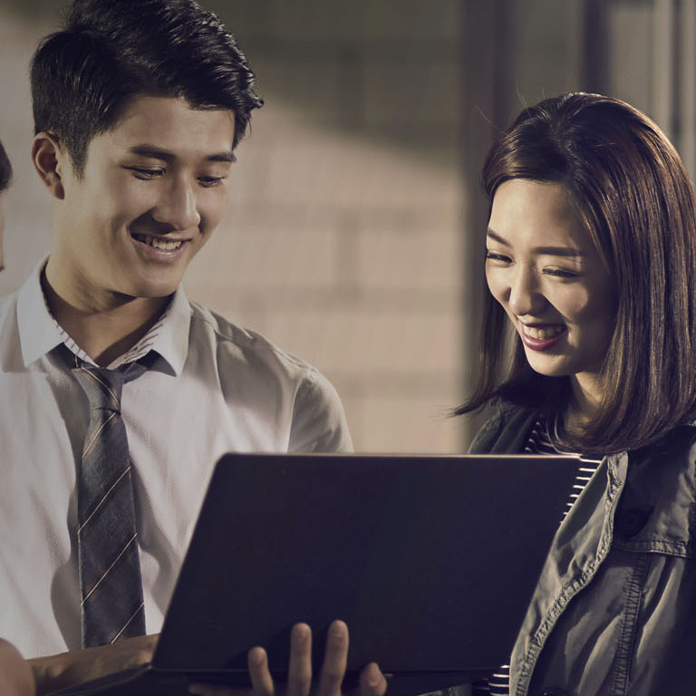 team of three young asian entrepreneurs meeting in office having a discussion using laptop computer in office