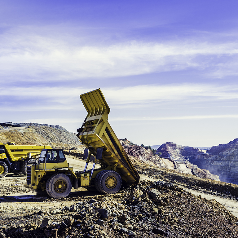 Dump truck tilting the ore load in the open pit mine of Riotinto with the cloudy sky in the background