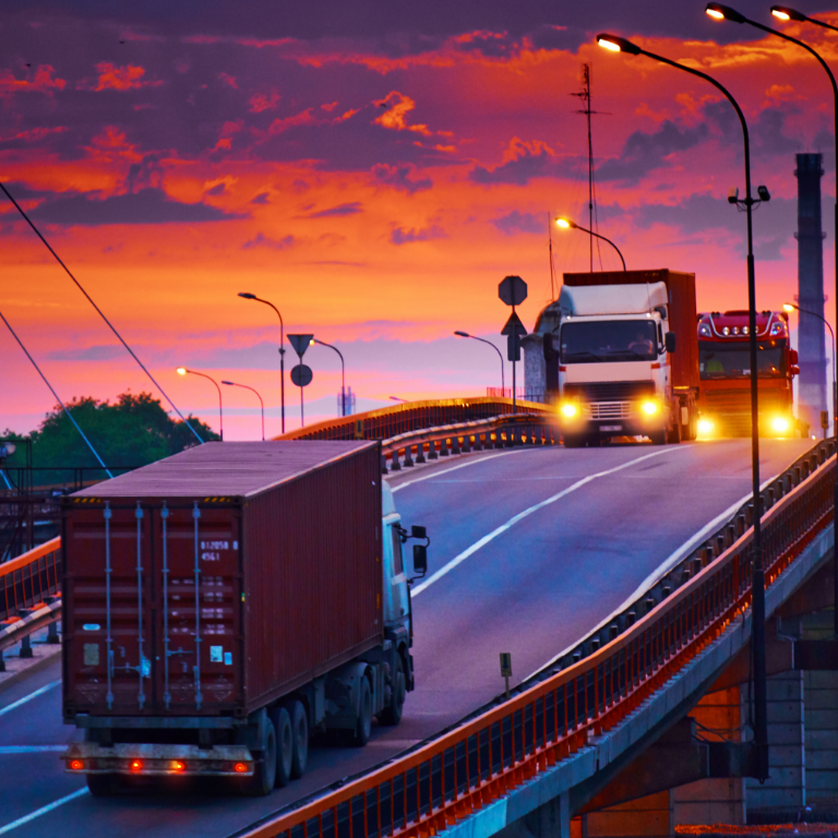 Truck with container rides on the road, railroad transportation, freight cars in industrial seaport at sunset