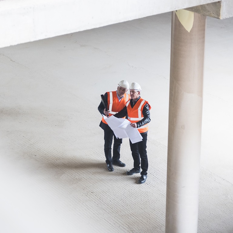 Two construction workers, wearing safety vests and helmets
