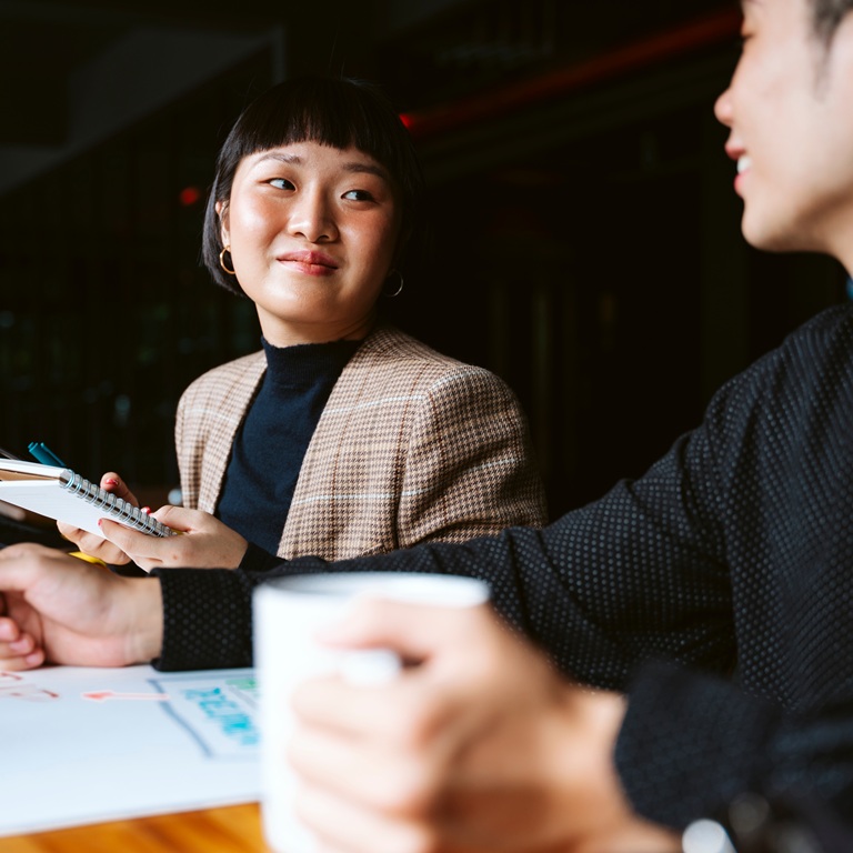 Two people sit at a table discussing their projects