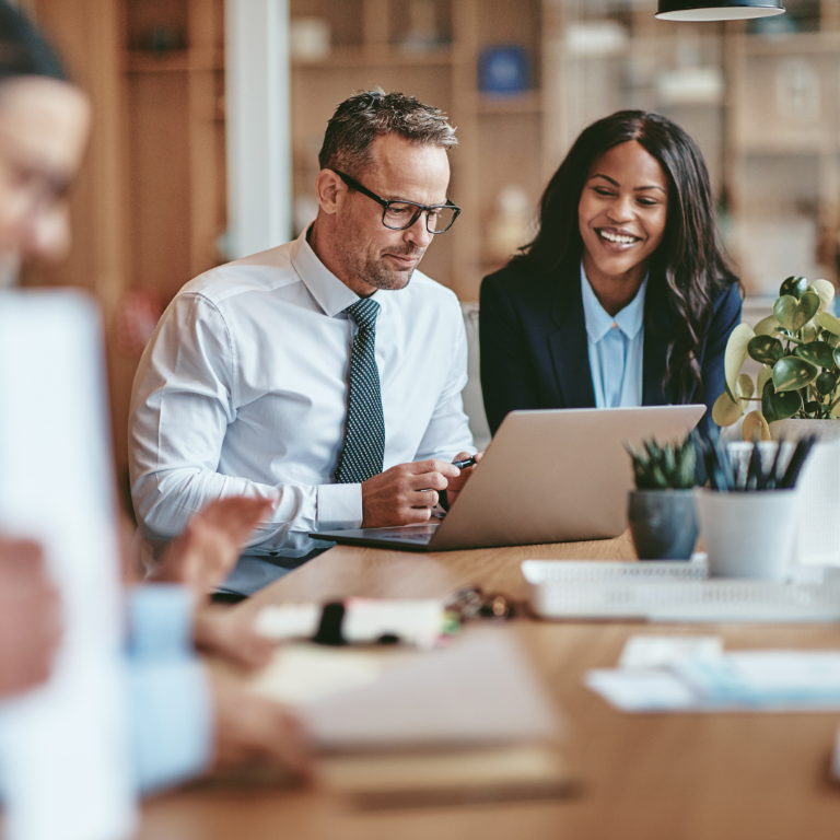 Two smiling diverse businesspeople using a laptop together