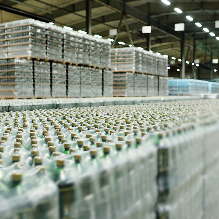 a huge industrial warehouse with plastic food wrap wrapped plastic bottles with carbonated drinks, water or beer.