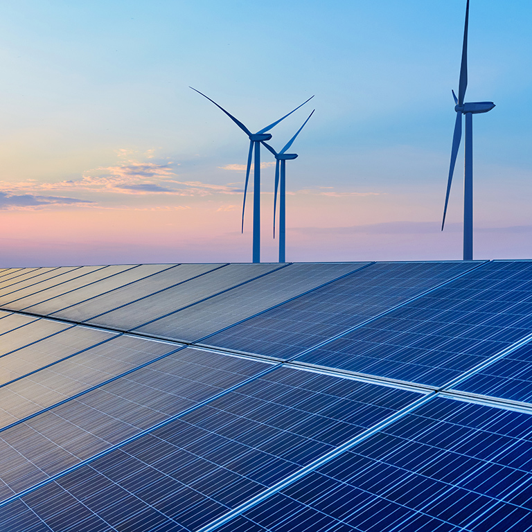 Solar panels and wind power generation equipment at sunset