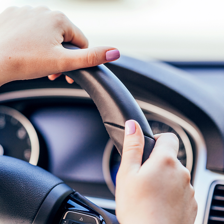 Close up of a woman's hands on steering wheel