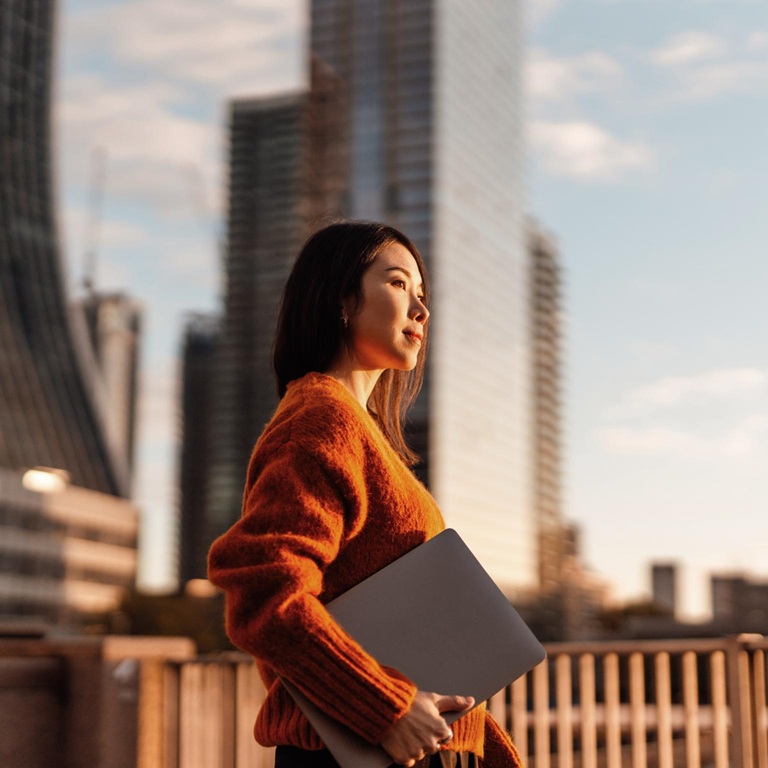 Woman holding laptop in city light 