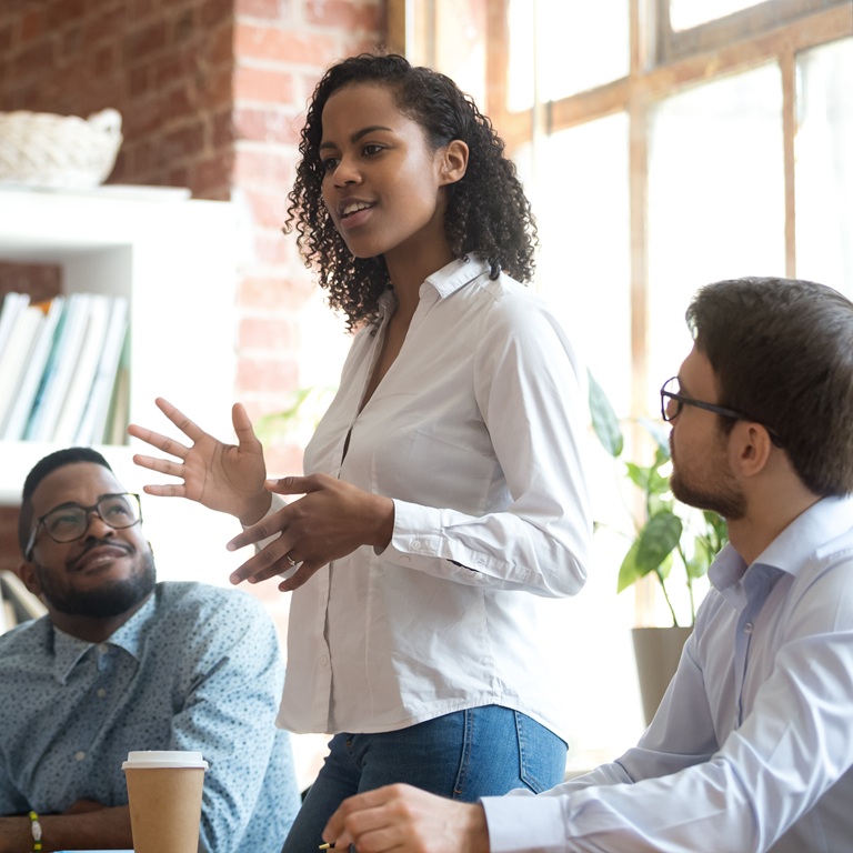 A woman passionately presents her ideas to a small group of attentive colleagues