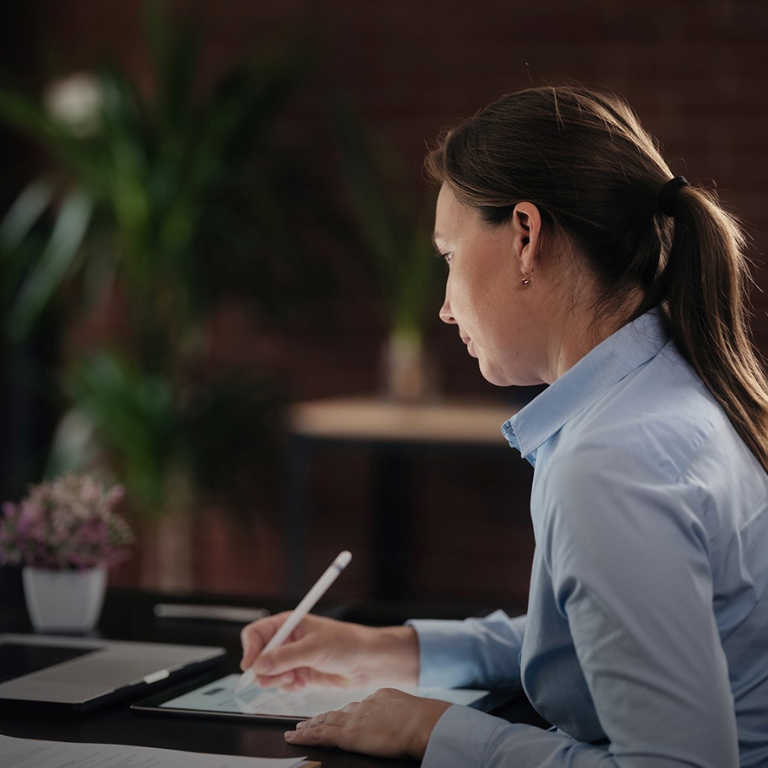 Woman studying on tablet and taking notes