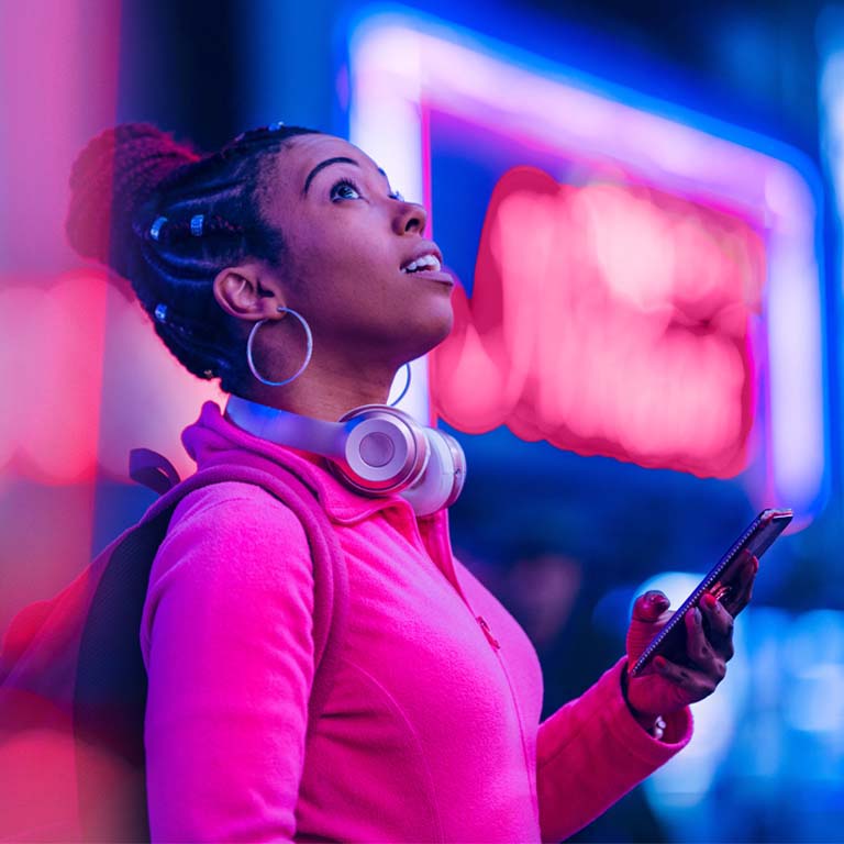 Woman using smart phone at night, neon setting in Japan