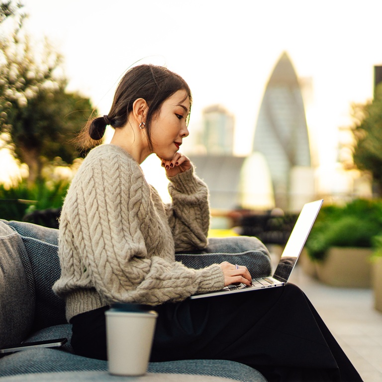 Woman working on laptop outdoors in urban setting