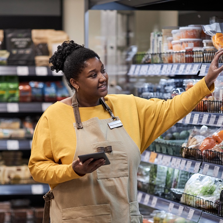 Worker arranges produce in grocery store during busy hours
