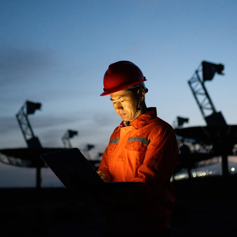 Worker looking at a laptop with anthenas behind