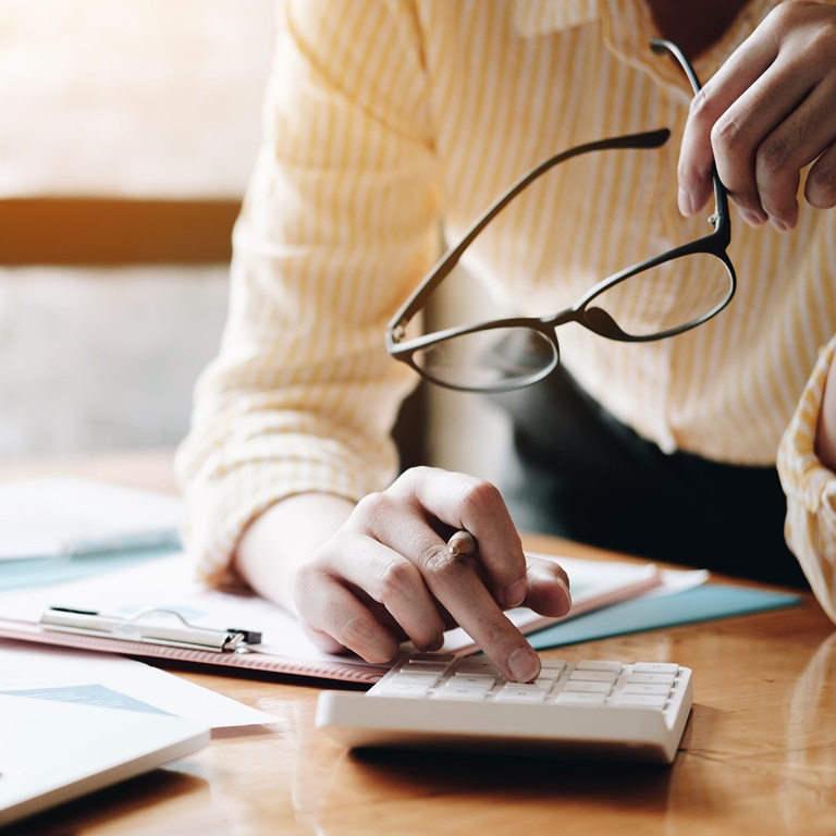 Close up Business woman using calculator and laptop for do math finance on wooden desk in office and business working background, tax, accounting, statistics and analytic research concept