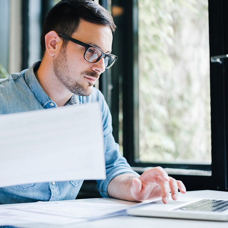 Young businessman in office working on laptop and documents