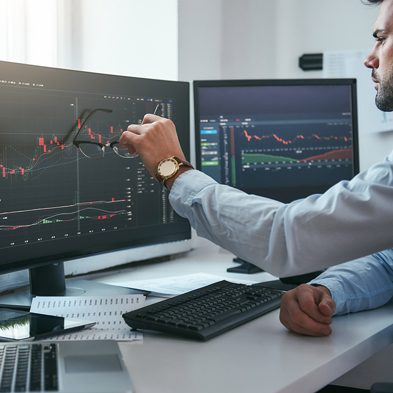 Forex market. Young trader is pointing at graphs on computer screen and analyzing data while working in his modern office. Stock exchange. Trade concept. Investment concept